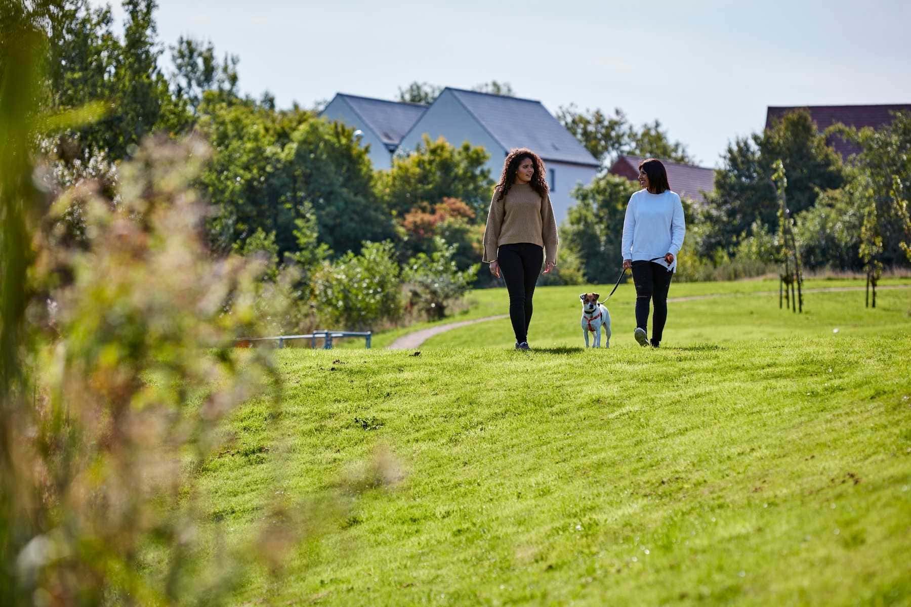 Mum and daughter walking dog in park