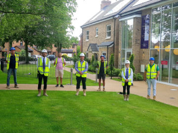 Workers posing on grass outside building