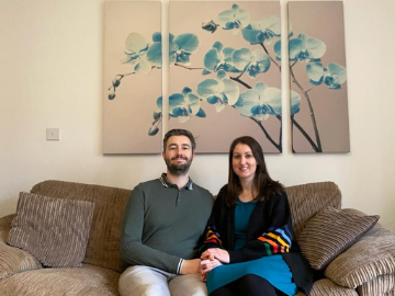 Couple on sofa in front of artwork
