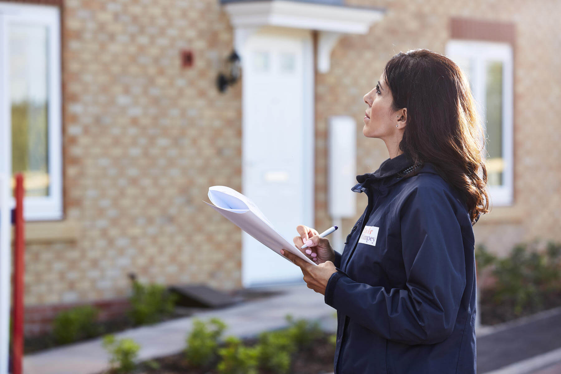 Lady looking at house with clipboard