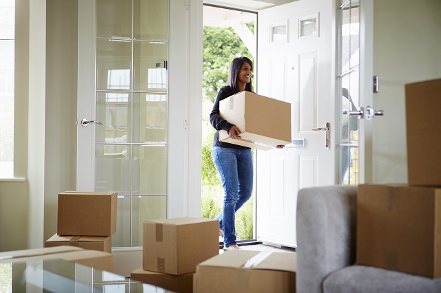 Woman carrying box through front door