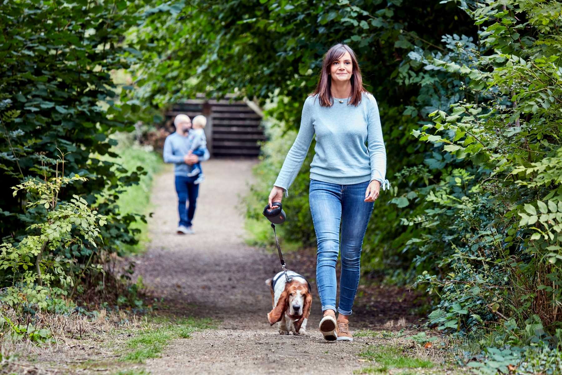 lady walking dog down woodland trail