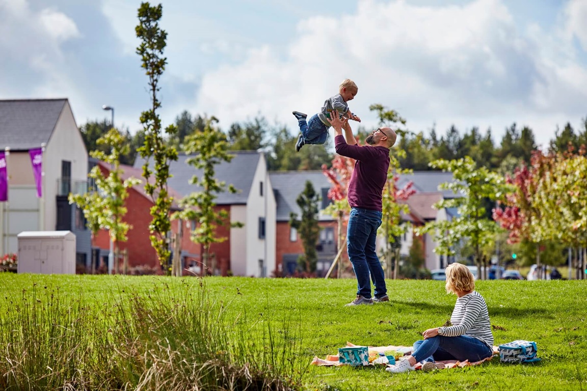 Family playing in green open space outside houses