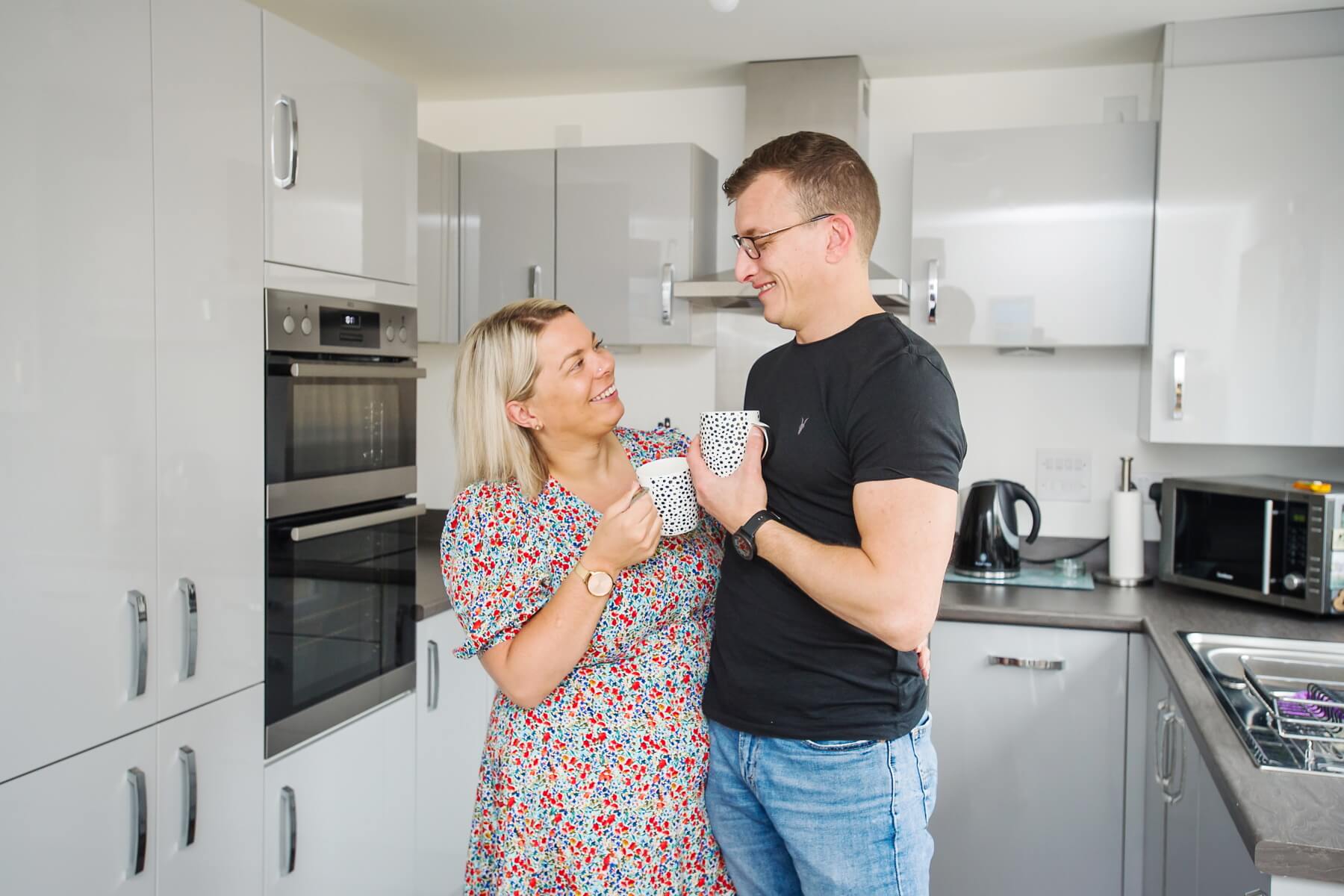 Couple toasting coffee mugs in their new home
