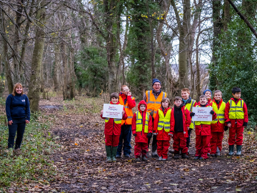 School children in woodland in high vis jackets