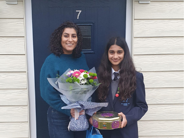 Mother and daughter holding bouquet of flowers outside front door