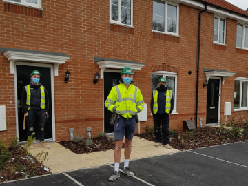 Men in high vis jackets outside new homes